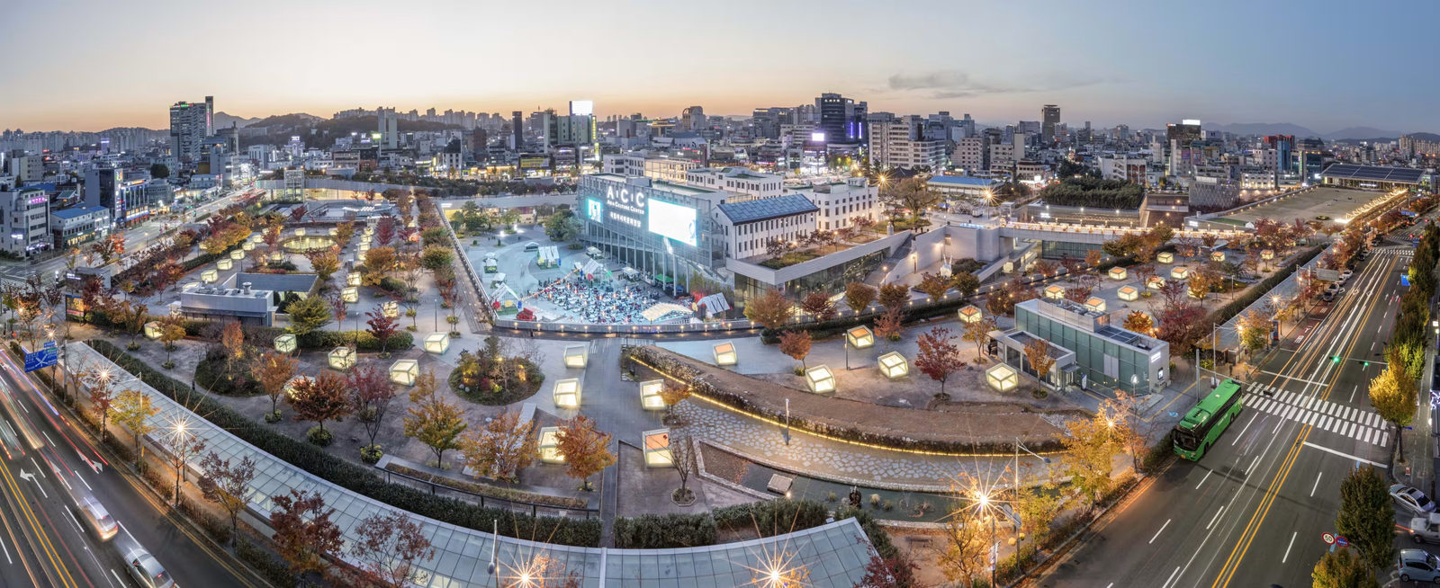 Panoramic view of central Gwangju at dusk, with the Asia Culture Center among lit streets and autumn trees.